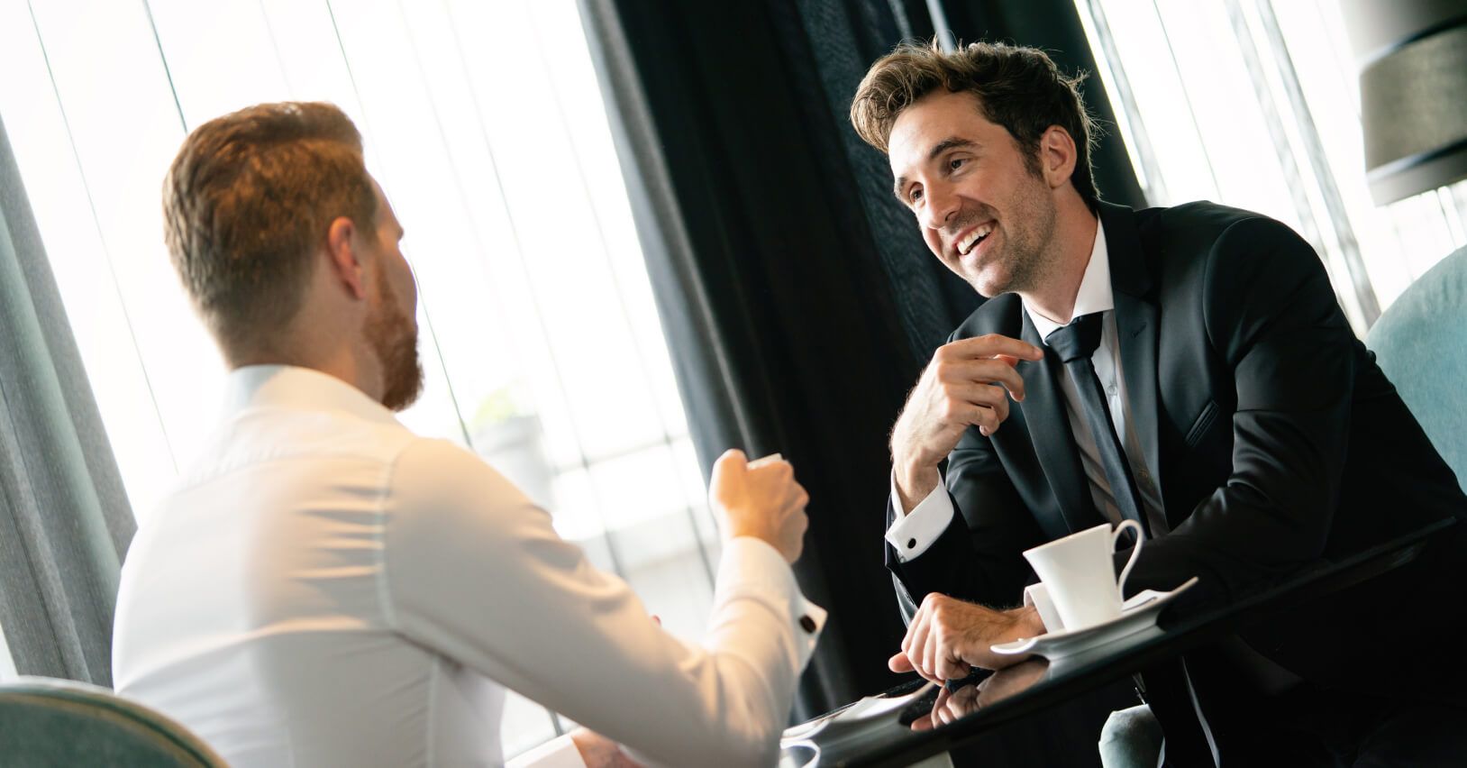 Rozmowa biznesowa dwóch mężczyzn w garniturach o pozyskiwaniu inwestorów i emisji akcji.